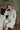 Pregnant woman wearing a pastel matcha Turkish cotton muslin robe in a sage green room