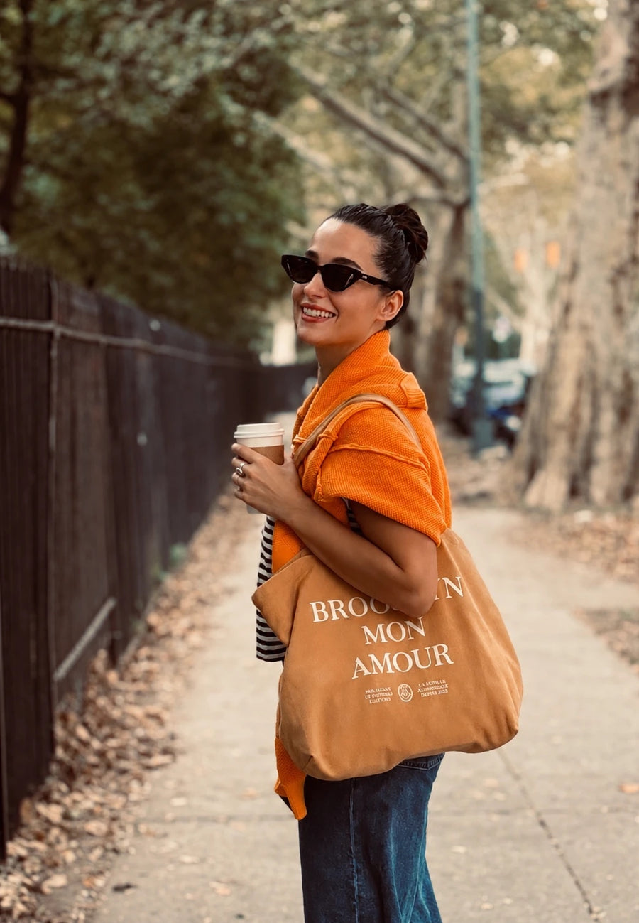 Nilan, founder of Replenish, with a coffee on a tree-lined Brooklyn street